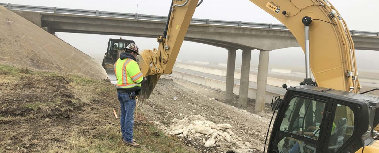 man standing next to excavator on IH 35E site